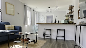 Een moderne keuken met een bar, houten vloer en een blauwe bank.