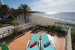 A beach view with two lounge chairs, a white fence, and palm trees. - Vacation Apartment 'Apartament Excepcional 1a Línea' with Sea View, Shared Pool and Wi-Fi (San bartolome de tirajana)