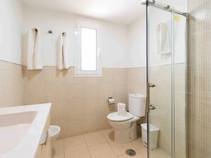Une salle de bain équipée d’une baignoire, de toilettes et d’une douche à parois de verre.