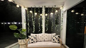 Un rincón acogedor con un banco acolchado, un tablero de ajedrez y plantas colgantes.