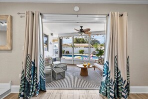 A balcony with a pool, wicker furniture, and a ceiling fan.
