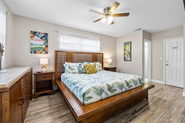 A bedroom with a wooden bed, a ceiling fan, a nightstand with a lamp, and a door labeled "Floors".