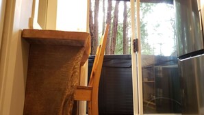 Habitació amb una cadira de fusta, una porta corredissa de vidre que dona a un balcó i un frigorífic d'acer inoxidable.