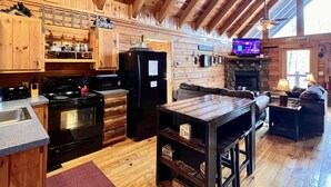 L’intérieur d’un chalet rustique comprenant une cuisine, un coin repas et un salon.