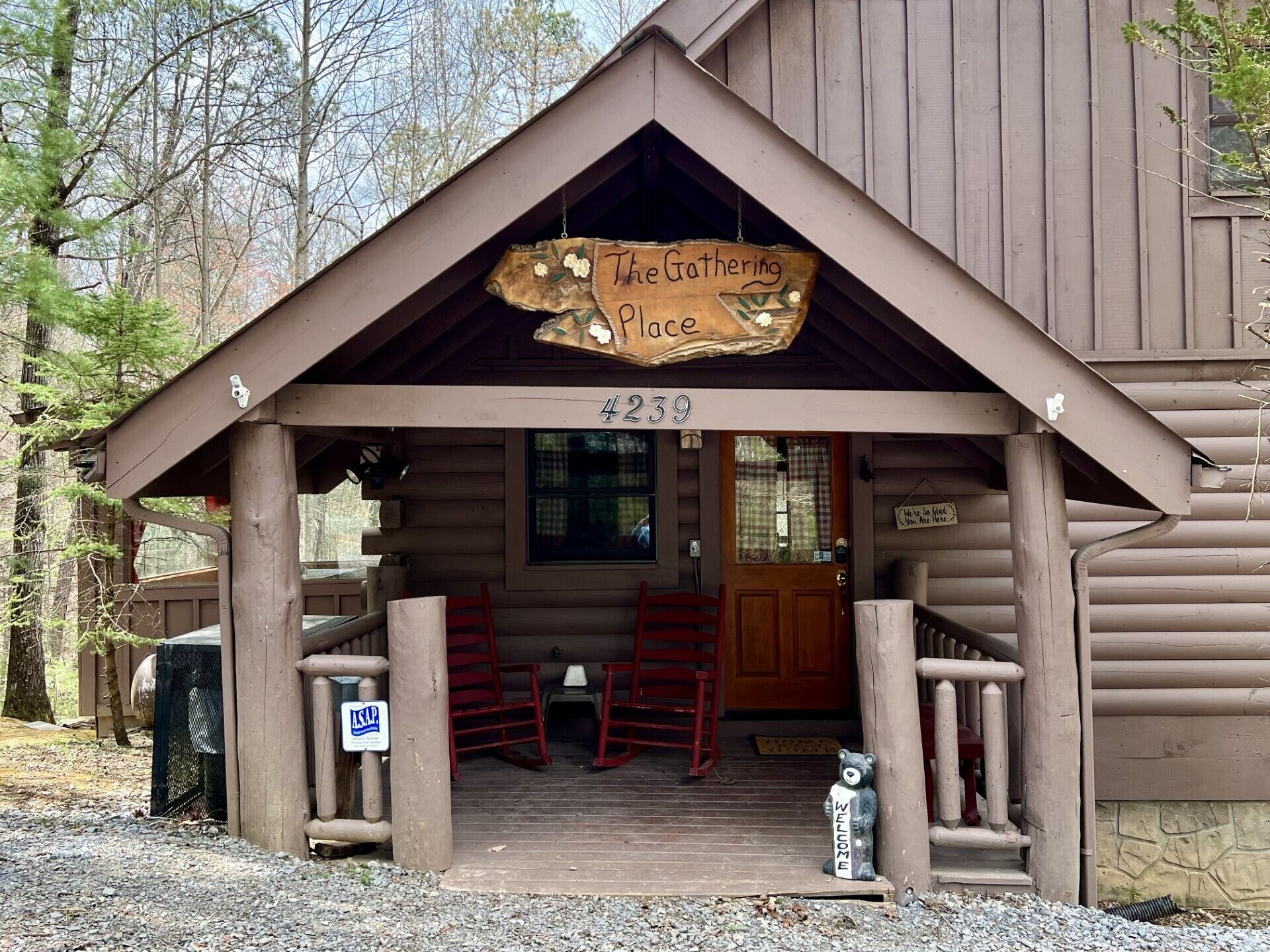 Una rustica baita di tronchi con un portico, un cartello di legno con su scritto "The Gathering Place" e una statua di un orso a suggello dell'accoglienza.