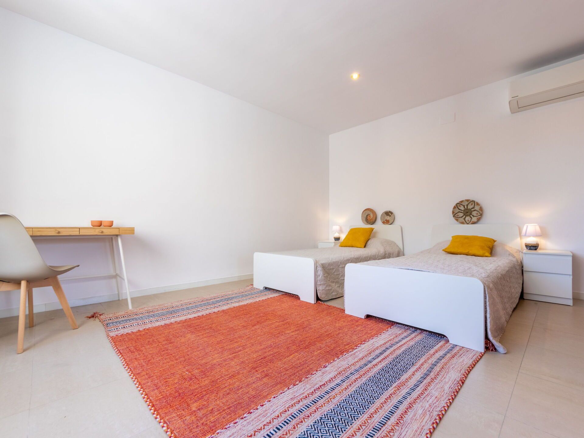 A bedroom with two beds, a desk, and a chair.
