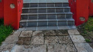A building with a large wooden door, a small window above the door, and a set of stone steps leading up to the entrance. - Hotel Hacienda Maravillas (Nopala)