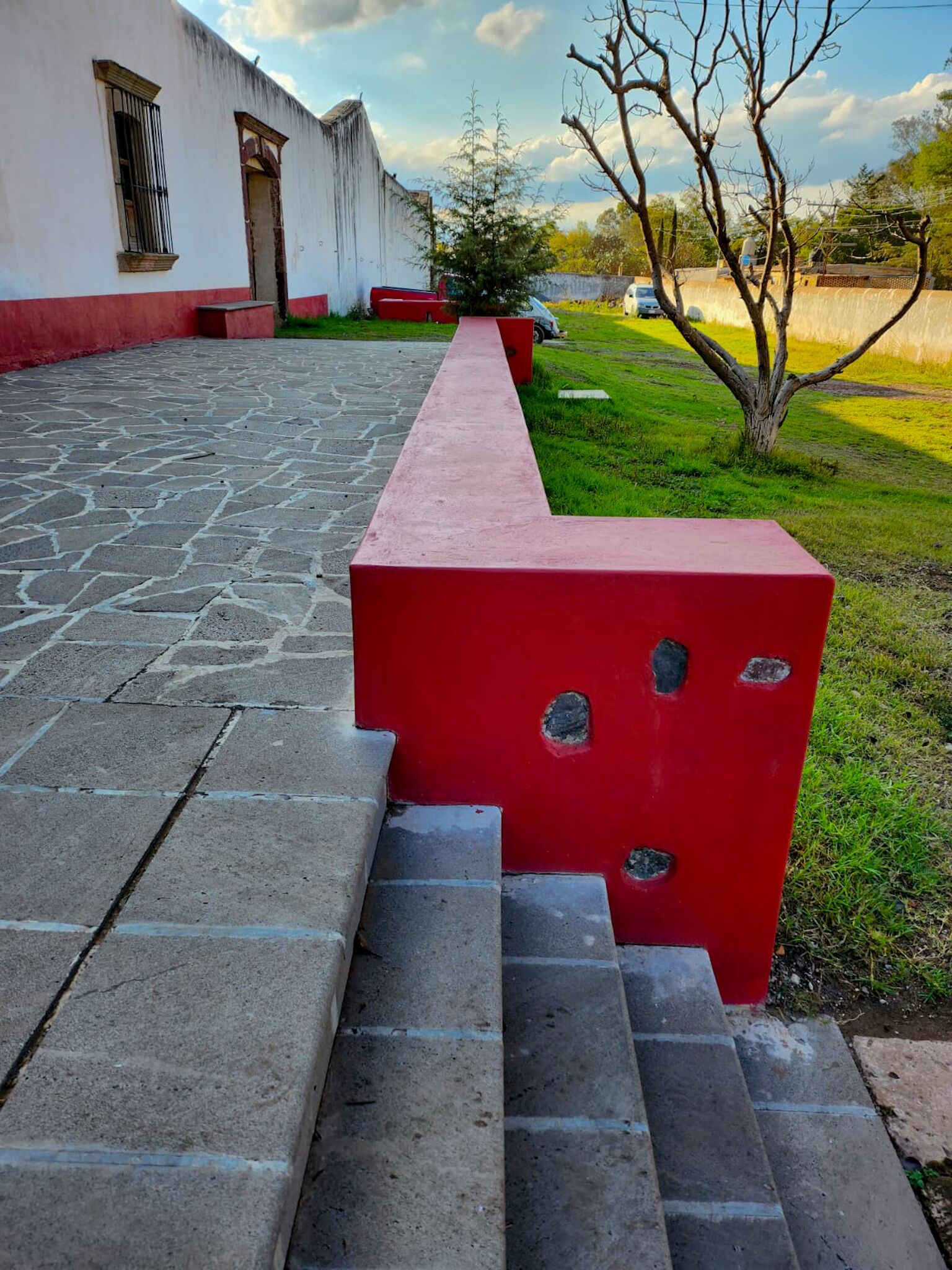 Un banc rouge avec des marches menant à un bâtiment blanc dont la base est rouge.