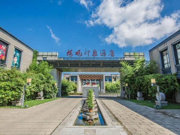 A building entrance with a sign in a foreign language, a pathway leading to the entrance, and a water feature in the foreground. - Impressions of Louuguan Resort Xi'an (Xi'an)