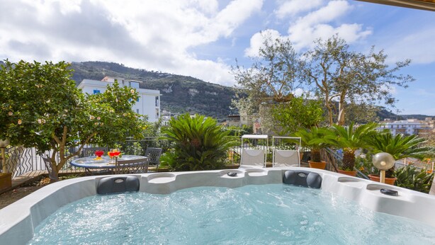 A hot tub with a view of a hillside and a table with chairs. - Maison Wally (Sorrento)