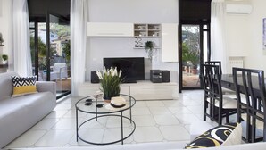 A modern living room with a sofa, coffee table, TV, and dining area. - Maison Wally (Sorrento)