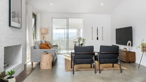 Una sala de estar moderna con chimenea, un sofá, dos sillones, una mesa de centro y un televisor en la pared.