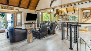 A spacious living area with leather sofas, a flat-screen TV, and a wooden ceiling.