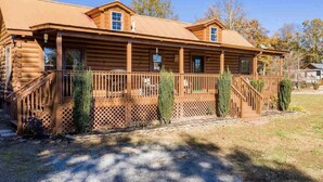 A log cabin with a porch, a covered front entrance, and a small attached structure. - Restoration Station: Where Landrum's past Inspires Renewal - 2Bed/2Ba Log Cabin (Landrum)