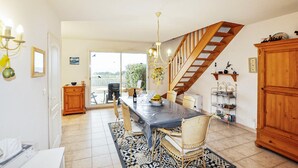 A dining area with a table, chairs, and a chandelier. There is a staircase with wooden railings leading to a balcony. - Amazing home in Saint Pierre La Mer with WiFi (Saint Pierre La Mer)