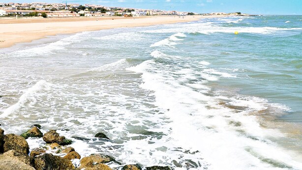 A beach with waves, rocks, and a distant town. - Amazing home in Saint Pierre La Mer with WiFi (Saint Pierre La Mer)