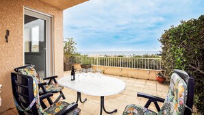 A balcony with a round table and chairs, a bottle of wine, and glasses. - Amazing home in Saint Pierre La Mer with WiFi (Saint Pierre La Mer)