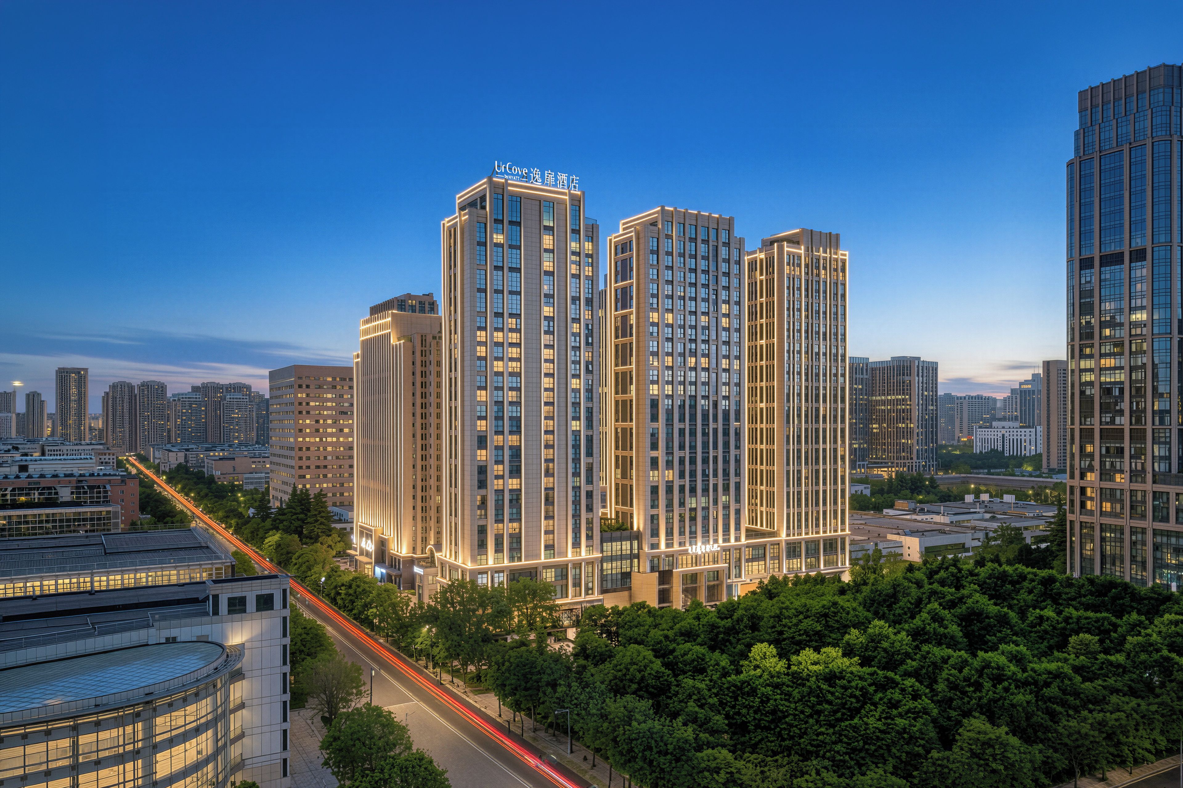 Un grand hôtel à plusieurs étages, entouré d’autres immeubles et d’arbres.