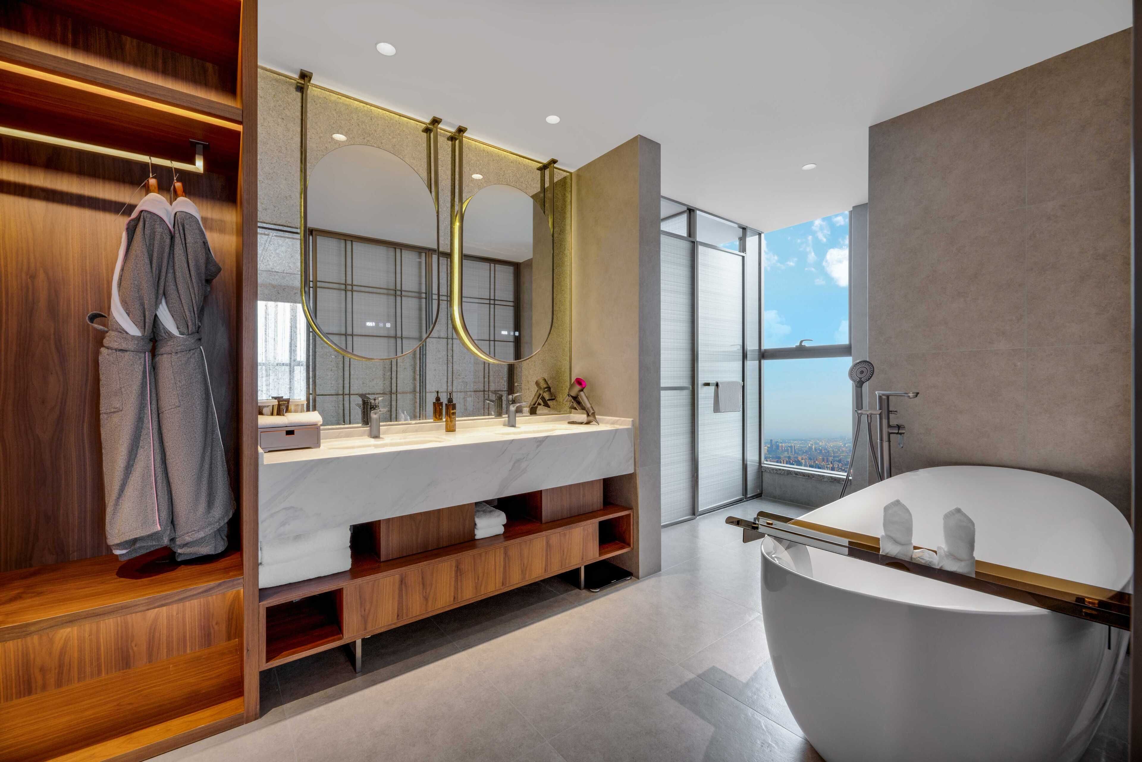 Une salle de bain moderne avec une baignoire sur pieds, un grand miroir et un meuble-lavabo doté d’un plan de travail en marbre.