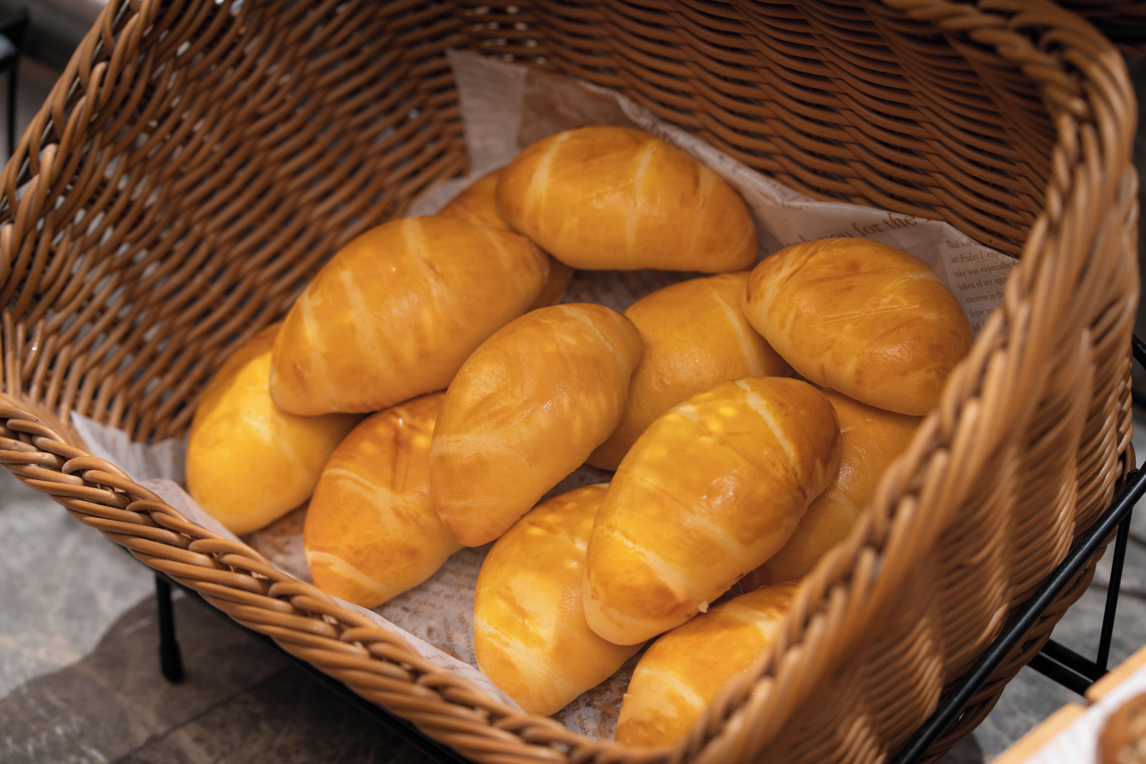 A wicker basket filled with golden-brown bread rolls.
