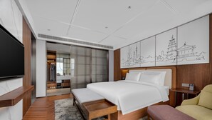 A modern hotel room with a large bed, a TV, a bench, and a wall with a cityscape mural. - UrCove by Hyatt Xi'an Hi-Tech CROSS Wanxianghui (Xi'an)