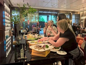Een moderne eetruimte met een lange tafel gedekt voor een maaltijd, omgeven door glazen scheidingswanden en een groot raam.