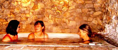 Three people in a stone-walled hot tub.