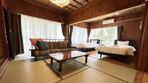 Een traditionele Japanse kamer met tatami vloeren, een bank, een bed en een houten salontafel.