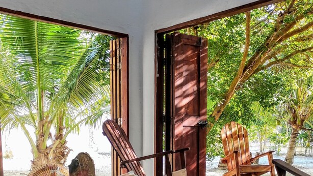 A room with a wooden table, chairs, and a view of a tropical garden. - La Caracola Cartagena  (Cartagena)