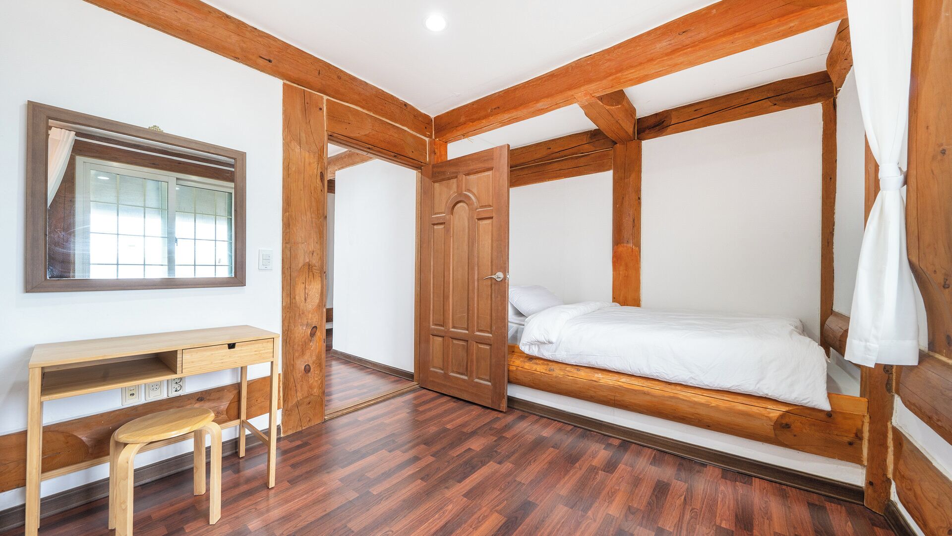 Una habitación con una cama de madera, un escritorio y una silla.