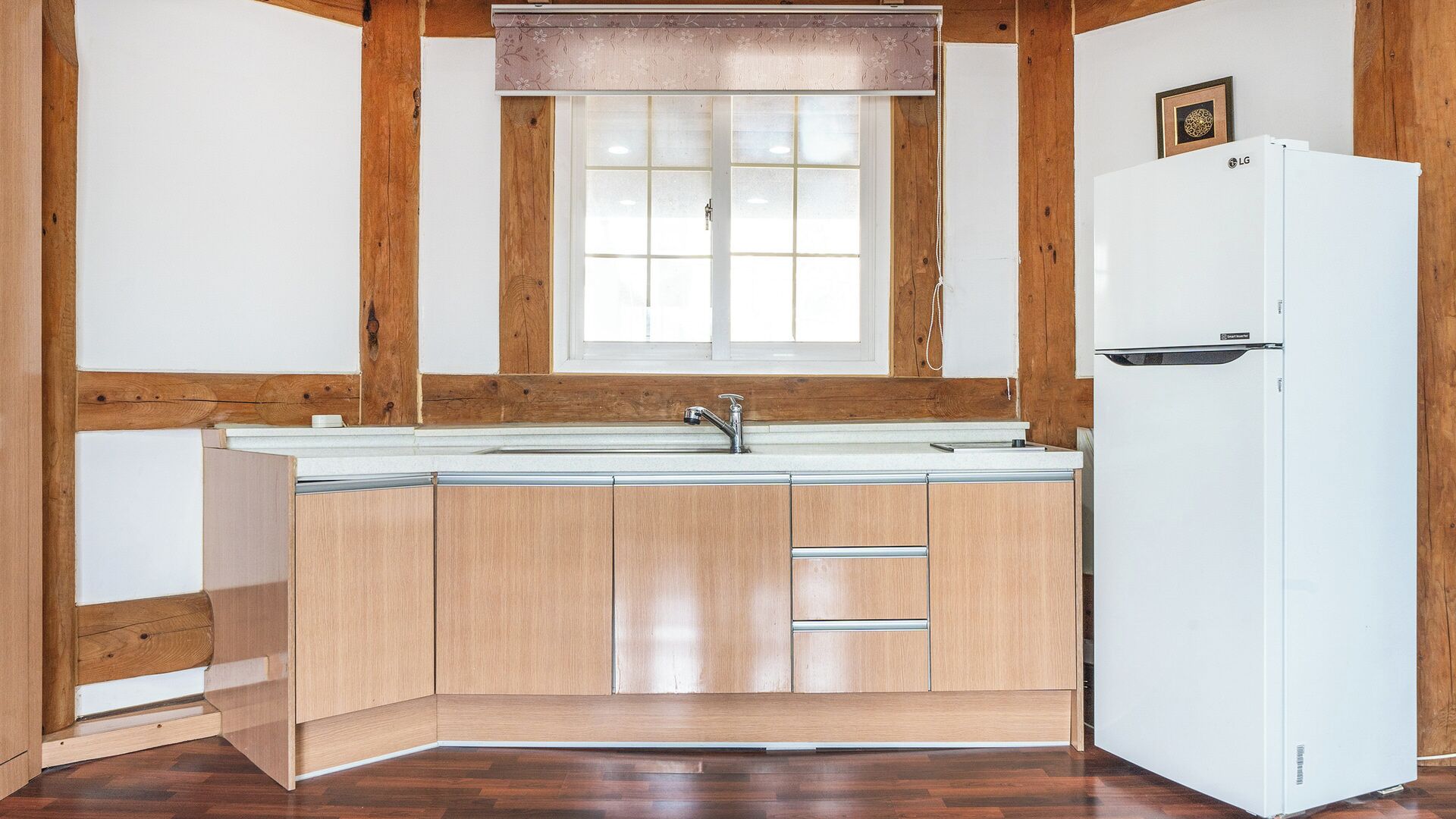 A kitchen with wooden cabinets, a white refrigerator, and a window above the sink.