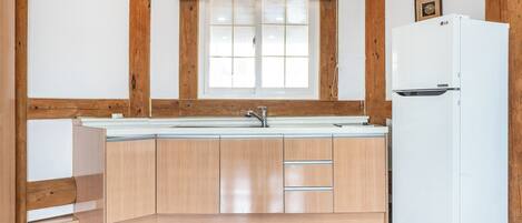 A kitchen with wooden cabinets, a white refrigerator, and a window above the sink.
