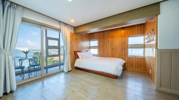 A bedroom with a large window, a bed, and wooden paneling. - Samcheok Jangho Sanho Pension (Samcheok)