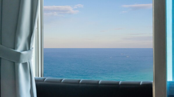 A view from a window with a curtain, overlooking a calm sea and a clear sky. - Samcheok Jangho Sanho Pension (Samcheok)