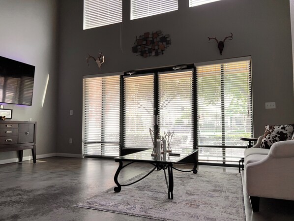 Relax in this stylish living room with a high ceiling, large windows, and a modern design.