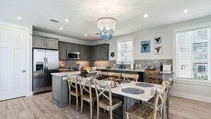 Una cocina moderna con una isla central, sillas de madera y una lámpara de araña.