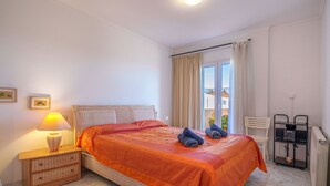 A neatly arranged bedroom with a bed, a bedside table with a lamp, a chair, and a radiator. - Magrana Over The Sea (Private Pool). by Interhome (Porto Cristo)