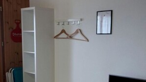 Una habitación con un banco blanco, un mueble para televisor y una televisión instalada en la pared.