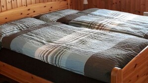 Una habitación de cabaña de madera con una cama, una lámpara y un cuadro en la pared.