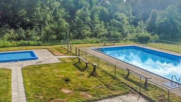Una piscina rectangular amb una zona de solàrium al voltant i una piscina més petita a la vora.