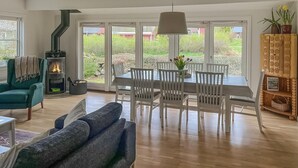 A spacious living area with a fireplace, dining table, and chairs. - 3 bedroom beautiful home in Hörby (Hörby)