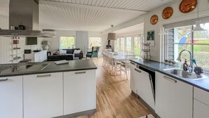 A modern kitchen with white cabinets, a central island, and a large window providing a view of the outdoors. - 3 bedroom beautiful home in Hörby (Hörby)