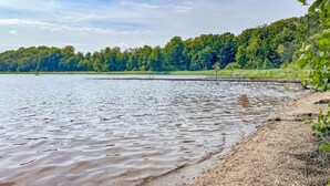 A calm lake with a sandy shore and dense forest in the background. - 3 bedroom beautiful home in Hörby (Hörby)