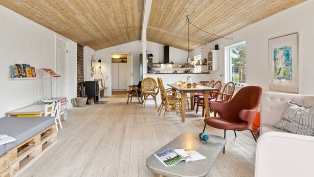 Een ruime woonkamer met een hoge plafond, een eettafel met stoelen, een bank en een salontafel.