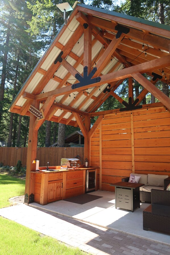 A wooden outdoor structure with a roof, a built-in bar area, and seating.
