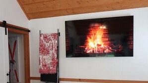 Ein Wohnzimmer mit Kamin, Fernseher, Sofa und Couchtisch mit Büchern.