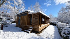 Une cabane en bois dotée d’un porche, entourée d’arbres couverts de neige.