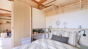 Une chambre à coucher avec un lit, un plafond en bois, une étagère avec des objets décoratifs et un mur au décor sobre.