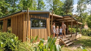 A wooden cabin with a porch, surrounded by greenery.
