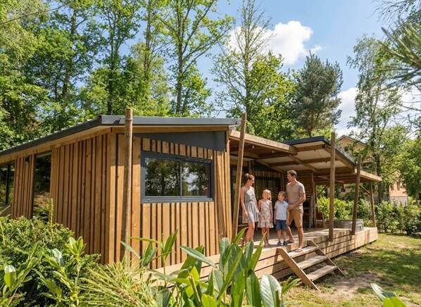 Uma cabana de madeira com varanda, rodeada por vegetação.